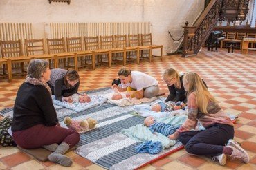Billede af babyer og mødre på gulvet i kirken